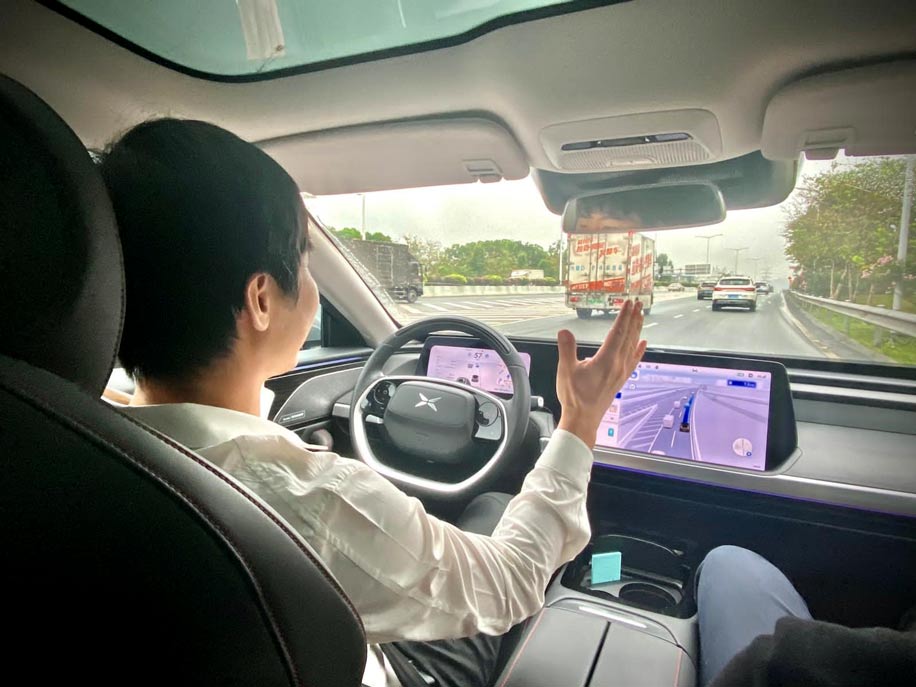 Man driving hands-free in an autonomous electric vehicle of a Chinese manufacturer.