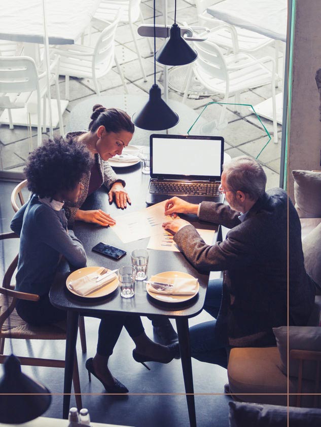 Group of 3 people casually working at a restaurant table.