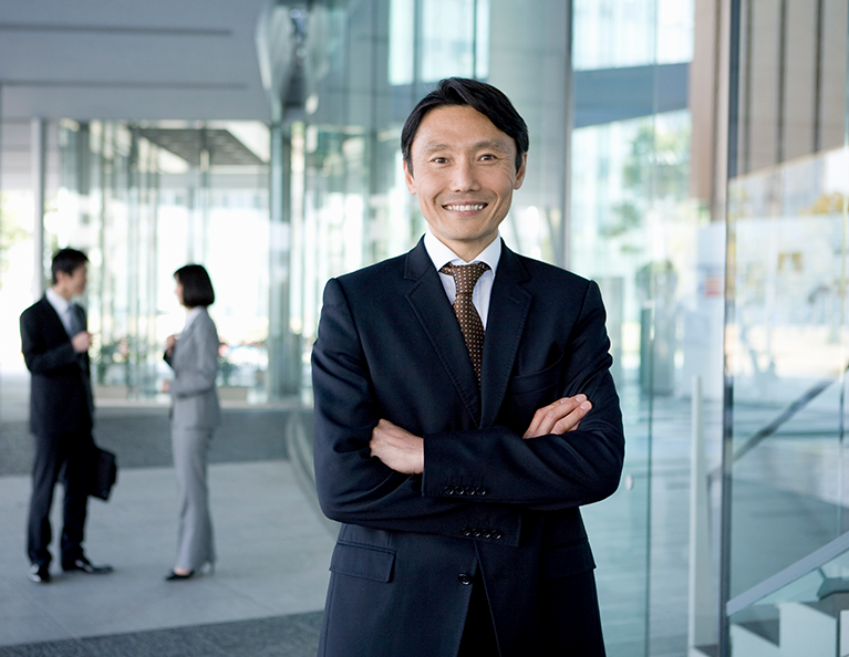 An asian man in a office, smiling at the camera